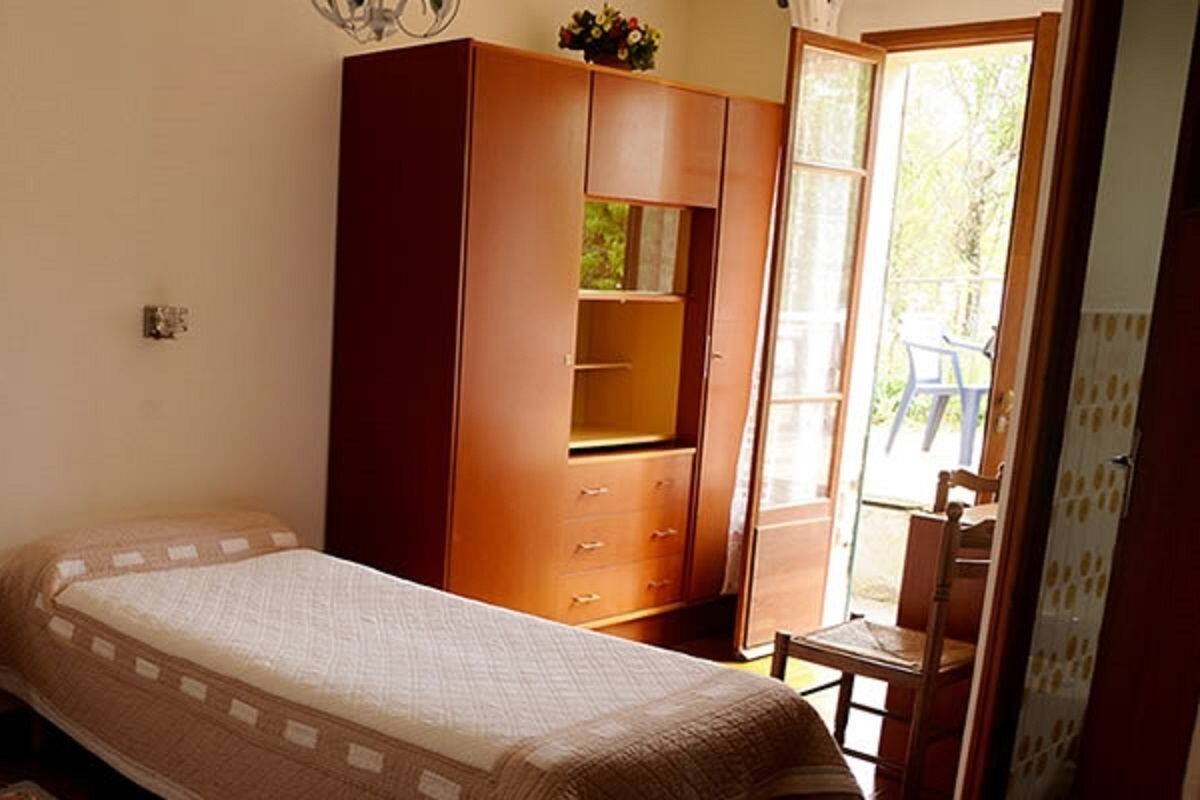 A bedroom with two single beds, a wooden wardrobe, and a small table.