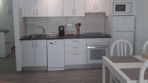 Una cocina moderna con armarios blancos, lavavajillas, horno, microondas y fregadero.