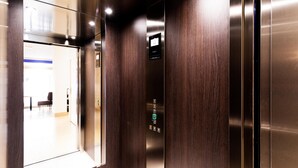 An elevator interior with a digital display, wooden paneling, and a glass door. - Le Theatre (Suresnes)