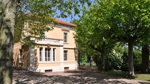 Un bâtiment à la façade symétrique, doté de grandes fenêtres et d’une entrée centrale.
