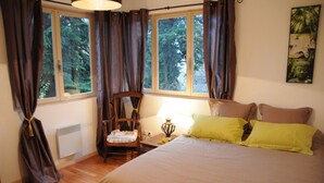 Une chambre à coucher avec un grand lit, une chaise, une table de chevet et une fenêtre avec des rideaux.