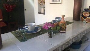 A kitchen counter with various items including a bowl, a wine glass, a vase with flowers, and a decorative bottle. - Private Casita, 1BR, A/C, 1 Block to the Best Beach in Zihuatanejo (Zihuatanejo)
