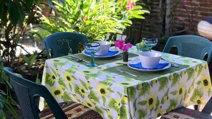 A table set outdoors with a sunflower tablecloth, surrounded by chairs and a potted plant. - Private Casita, 1BR, A/C, 1 Block to the Best Beach in Zihuatanejo (Zihuatanejo)