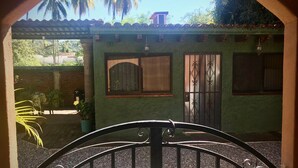 A gated entrance to a building with a green facade, a tiled roof, and two windows with decorative metal grilles. - Private Casita, 1BR, A/C, 1 Block to the Best Beach in Zihuatanejo (Zihuatanejo)