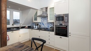 A modern kitchen with white cabinets, a black countertop, a built-in microwave, and a large window overlooking the city.