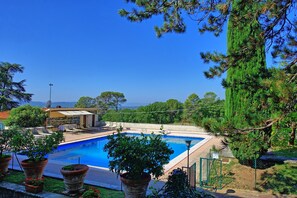 A swimming pool with a view of the sea, surrounded by potted plants and a building with a tiled roof. - Villa Cuculo - Holiday villa with swimming pool in Valdichiana, Tuscany (Patrignone)