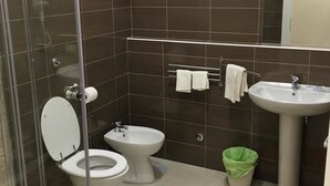 Un bagno con doccia vetrata, un water, un bidet e un lavandino.