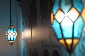 Dichtbij een hanglantaarn met een geometrisch patroon, een stenen muur met bogen en een vage achtergrond.
