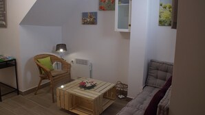 Un salon chaleureux avec un fauteuil en osier, une table basse en bois et un canapé confortable.