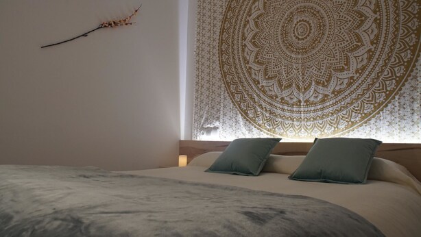 Une chambre à coucher avec un lit, des oreillers, une tapisserie murale et une décoration en forme de branche.