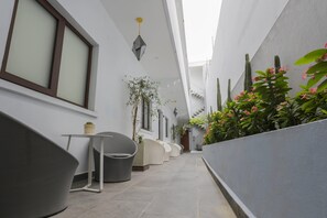 Seating areas and planters line the corridor, offering a peaceful retreat with comfortable seating and lush greenery.