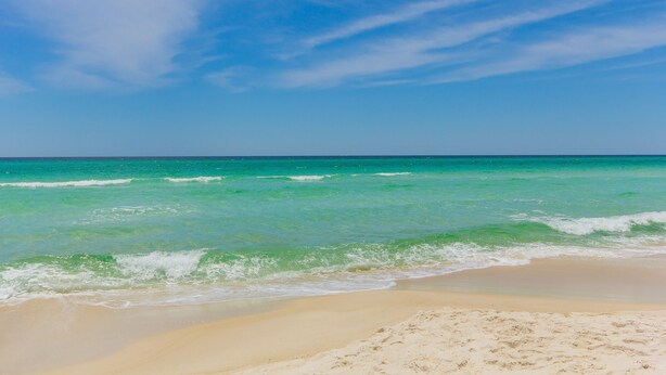 Une plage à l’eau turquoise et limpide, bordée d’un rivage sablonneux.