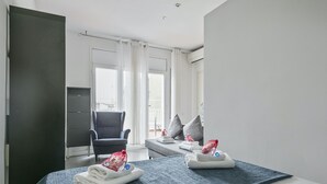 Ett hotellrum med en säng, en stol, en soffa och utsikt över omgivningarna.