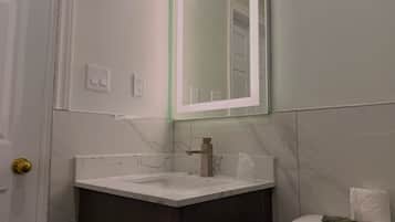 A bathroom with a marble sink, a mirror, a toilet, and a door with a golden handle.