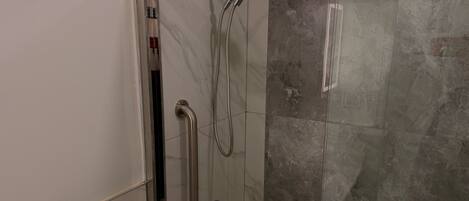 Eine Duschkabine mit Handbrause und Handtucharmatur.
