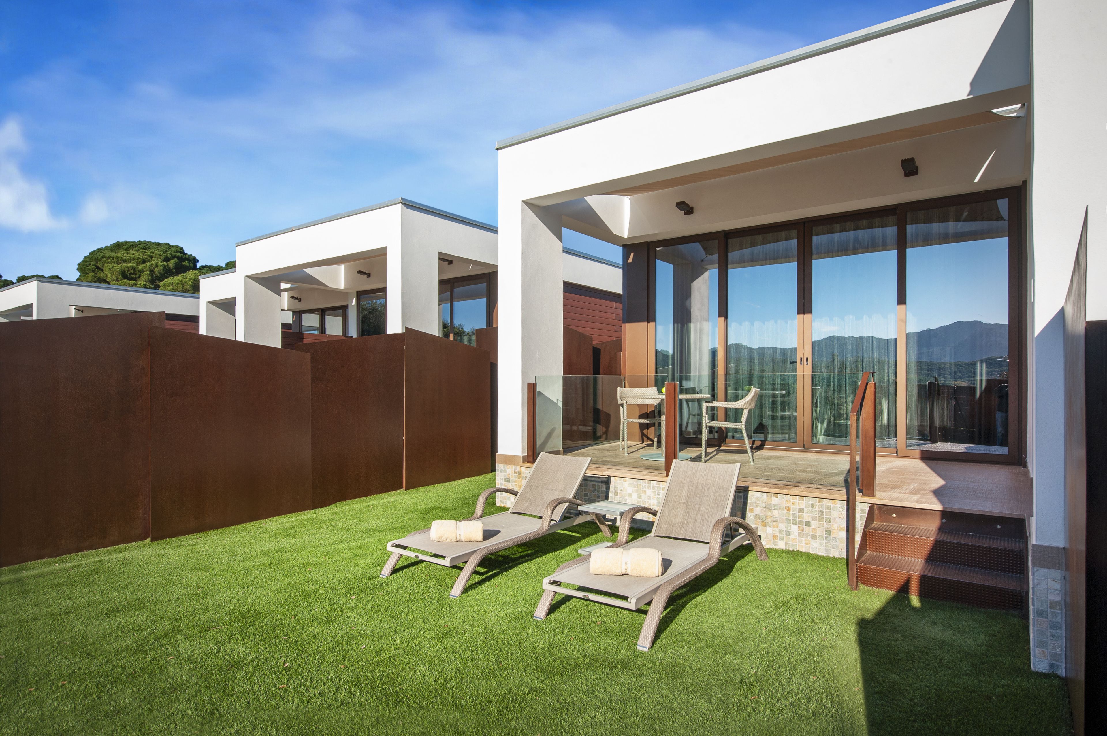 Un espacio exterior moderno con dos sillones de descanso, una mesa de patio y vistas a las montañas.