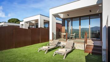 Un espacio exterior moderno con dos sillones de descanso, una mesa de patio y vistas a las montañas.