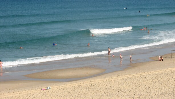 A beach with people swimming and walking along the shore. - Apartment with garden (Carcans Plage)