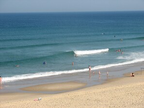 A beach with people swimming and walking along the shore.