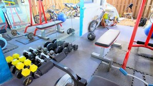 Una palestra in casa con attrezzature da allenamento, tra cui manubri, una panca e una cyclette.