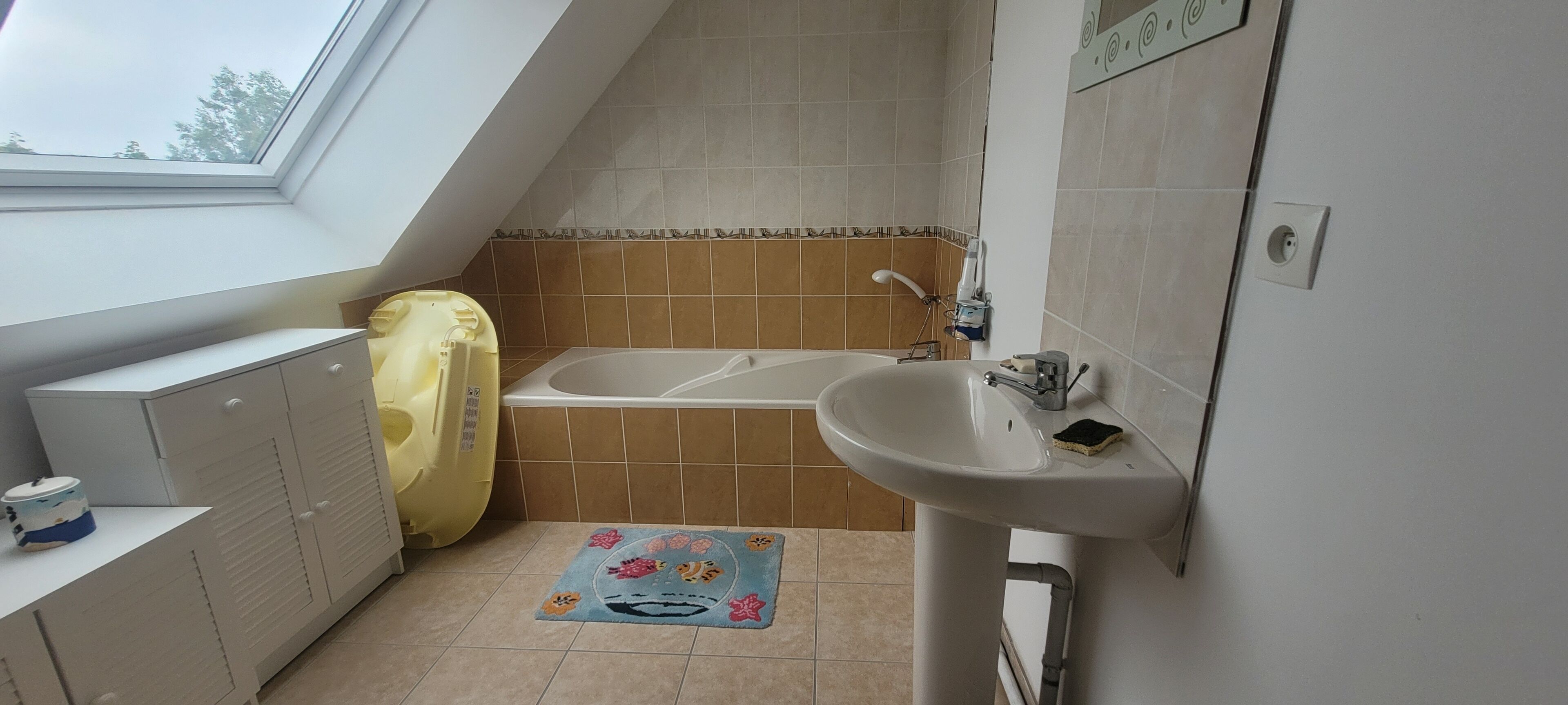 Une salle de bain avec un puits de lumière, une baignoire, un lavabo et des toilettes.