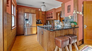 Eine Küche mit Holdekor, einem Edelstahlkühlschrank, einer Arbeitsplatte aus Granit und einer hölzernen Sitzbank.