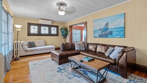 Ein Wohnzimmer mit einem braunen Ledersofa, einem beigen Sofa, einem Couchtisch und einem Bild eines Segelboots an der Wand.