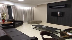 A modern living room with a sofa, a coffee table, and a TV mounted on the wall.
