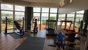 A gym with exercise equipment, large windows, and a view of a lake.