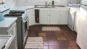 Eine kleine Küche mit weißen Schränken, einem Herd, einer Spüle und einem Kühlschrank.
