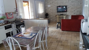 A compact living space with a kitchen, dining area, and a red sofa. - Sítio em Araçoiaba da Serra (Araçoiaba da Serra)