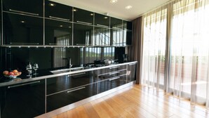 Een moderne keuken met een zwart aanrecht, roestvrijstalen apparatuur en een houten vloer.