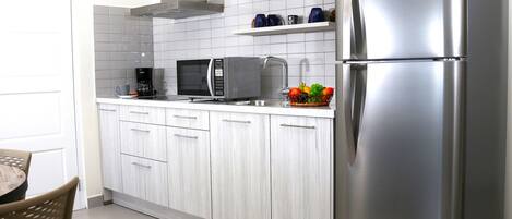 A modern kitchen with a stainless steel refrigerator, a microwave, and a coffee maker on the countertop.