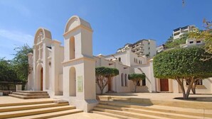 A building with a central tower, steps leading to the entrance, and a clear sky. - Antigua de Cabo (Cabo San Lucas)