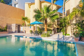 Una piscina al aire libre, sombrillas, sillones reclinables de piscina