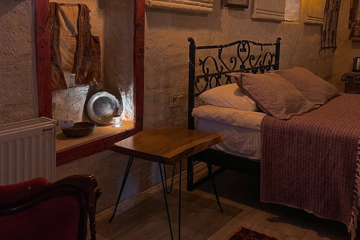A cozy room with a bed, a wooden table, and a mirror.