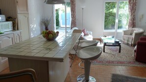A kitchen with a tiled backsplash, a fruit bowl on the counter, a bar stool, and a dining area with a table and chairs. - Charming 3 bedrooms cottage with a pool  for a typical experience in Provence (Saint-Rémy-de-Provence)