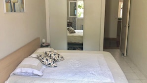 A bedroom with a bed, pillows, a painting, and a door leading to another room. - Charming 3 bedrooms cottage with a pool  for a typical experience in Provence (Saint-Rémy-de-Provence)