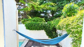 A hammock tied between a white wall and a wooden deck with a pool in the background. - Charming 3 bedrooms cottage with a pool  for a typical experience in Provence (Saint-Rémy-de-Provence)