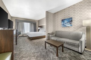 Una habitación de hotel con cama, sofá, escritorio y televisión.