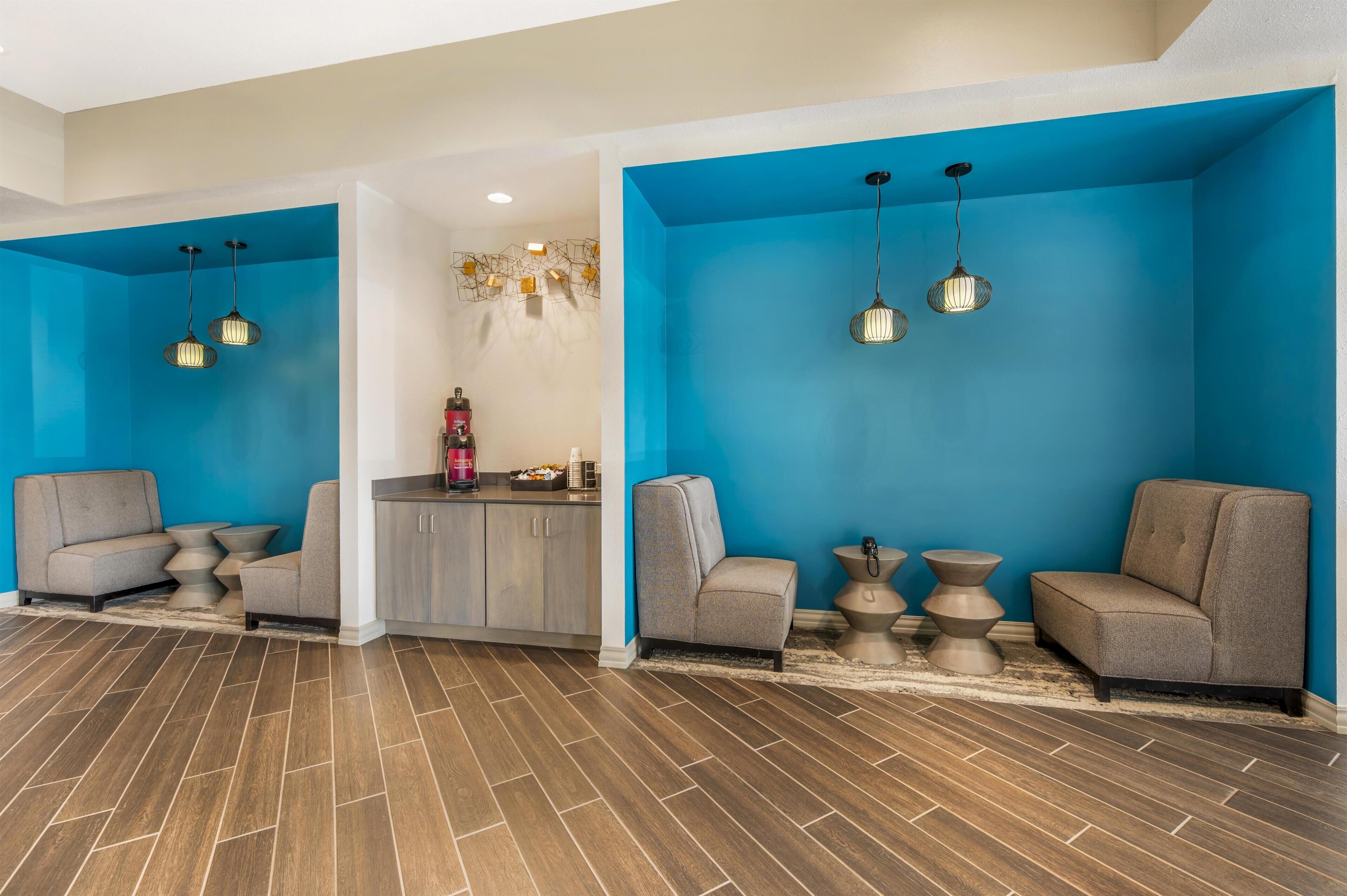 A modern lobby with two seating areas, a reception desk, and a kitchen area.