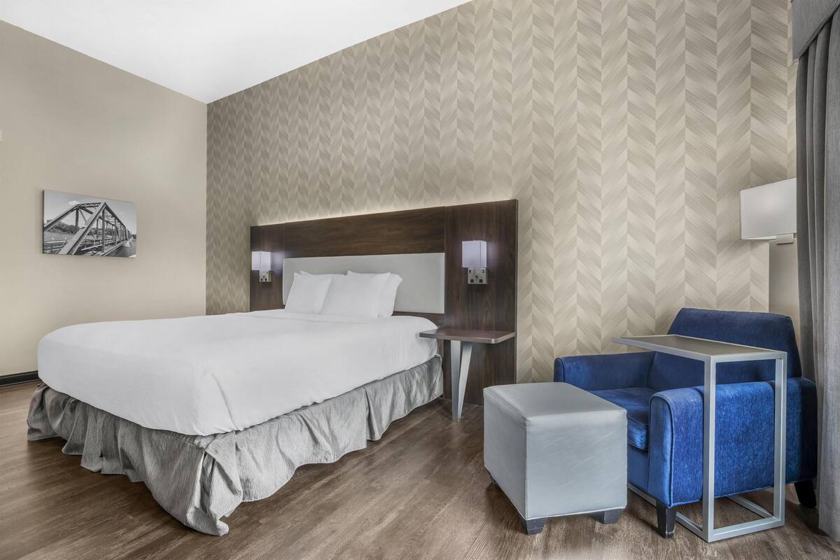 Habitació d'hotel amb un llit gran, un escriptori, una cadira i una taula petita.