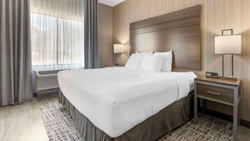 A hotel room with a large bed, two bedside tables with lamps, a window with curtains, and a patterned rug.