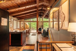 A spacious kitchen with a dining area, a large wooden ceiling, and a view of the outdoors.