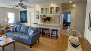 Ein Wohnzimmer mit blauem Sofa, Couchtisch aus Holz und Deckenventilator.