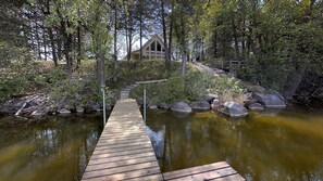 A wooden dock leading to a house surrounded by trees and a pond. - Lakefront Hideaway (Litchfield)