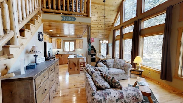 A cabin interior with a kitchen, dining area, and a living room with a sofa and a lamp. - Lakefront Hideaway (Litchfield)
