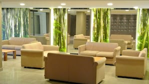A modern lobby with beige sofas arranged in a semi-circle, a wooden coffee table, and a glass partition with a bamboo backdrop. - ONE OF THE MOST BEAUTIFUL VIEWS OF NICE / MONT BORON / BASSE CORNICHE -  (Nice)