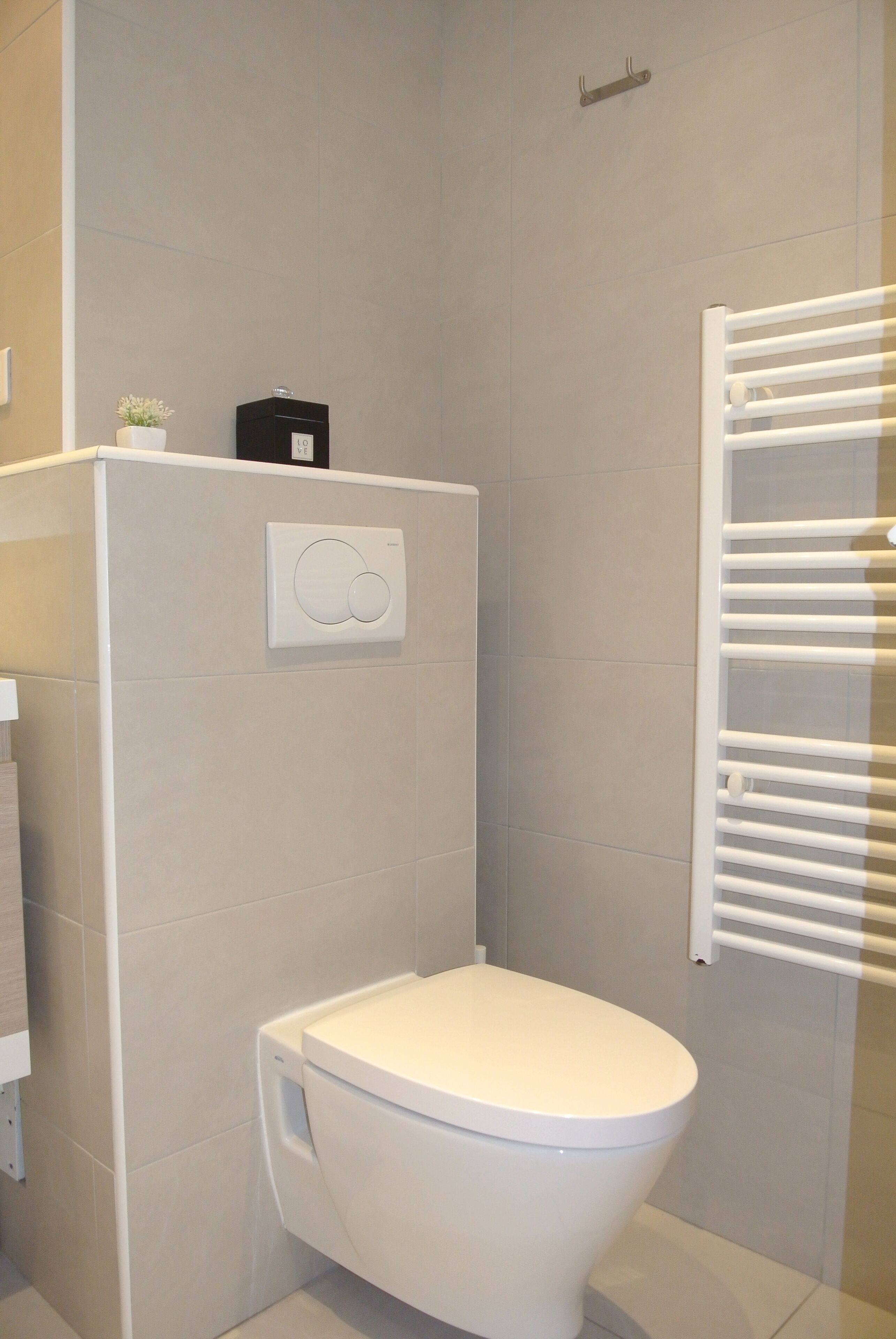 Un baño moderno con inodoro, perchero y panel de control en la pared.