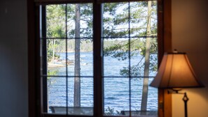 A window with a view of a lake and trees. - Beachfront 1-bedroom home, 15-min. drive to Traverse City.  Private and peaceful (Traverse City)